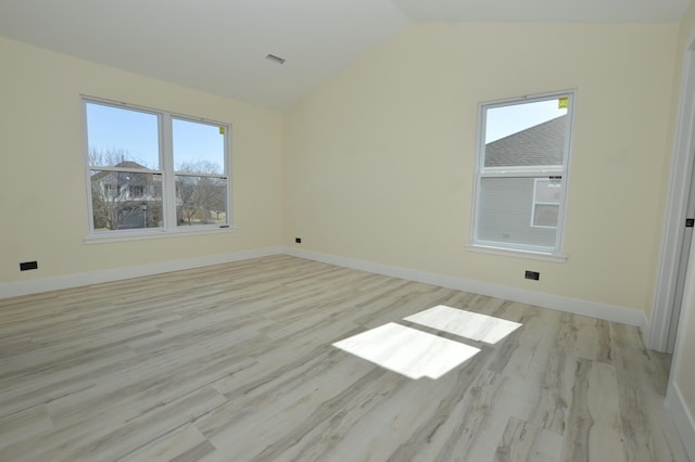 spare room with baseboards, light wood-style floors, and lofted ceiling