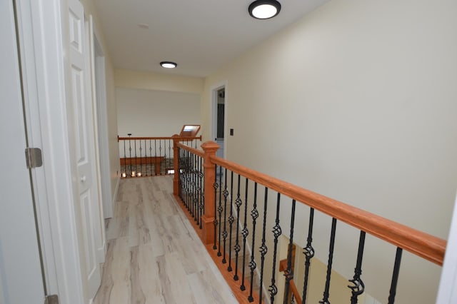 corridor with an upstairs landing and light wood-style floors