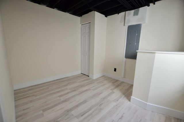 unfurnished room with electric panel, baseboards, and wood finished floors