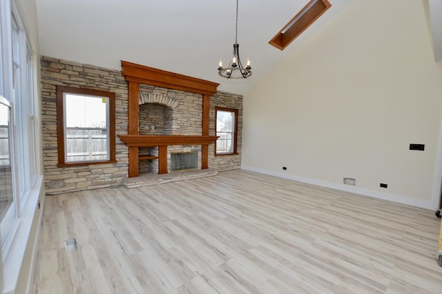 unfurnished living room featuring baseboards, a stone fireplace, an inviting chandelier, wood finished floors, and high vaulted ceiling