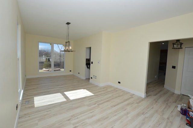 unfurnished dining area with light wood-style flooring, baseboards, and a chandelier