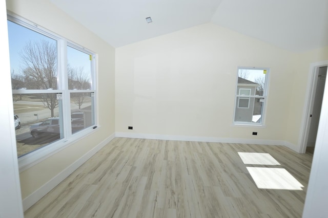 empty room with vaulted ceiling, wood finished floors, and baseboards