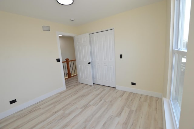 unfurnished bedroom featuring a closet, baseboards, and wood finished floors