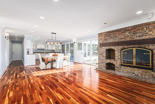 unfurnished living room featuring ornamental molding, dark hardwood / wood-style floors, and a brick fireplace