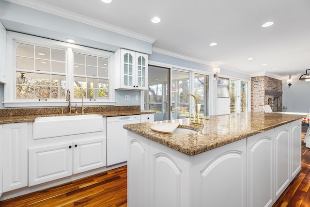 kitchen featuring white dishwasher, a healthy amount of sunlight, dark stone countertops, and sink