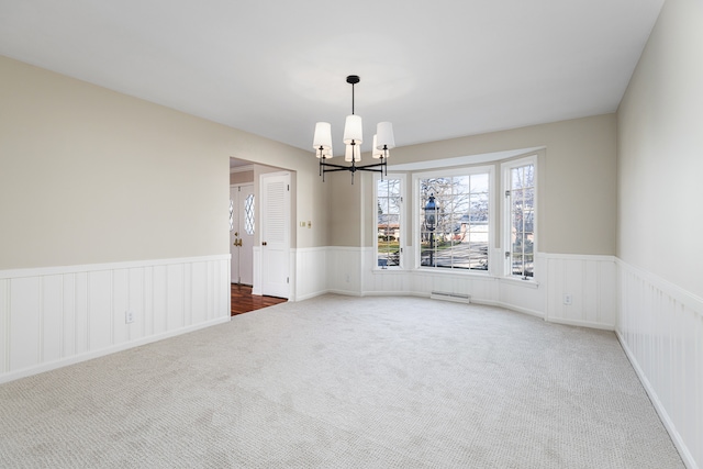 carpeted empty room featuring an inviting chandelier