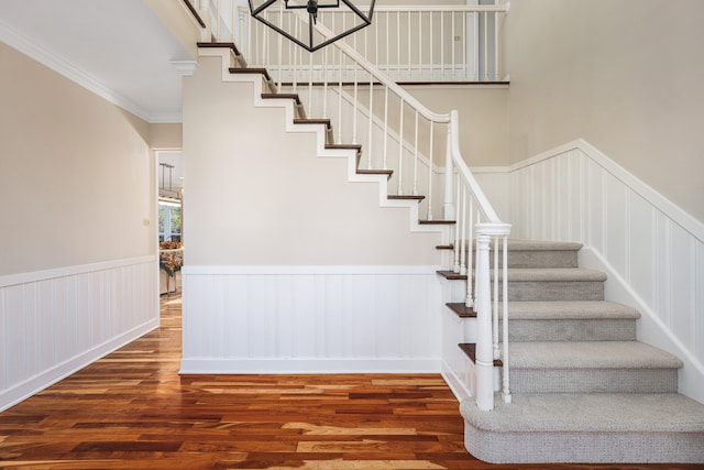 stairs with hardwood / wood-style floors and ornamental molding