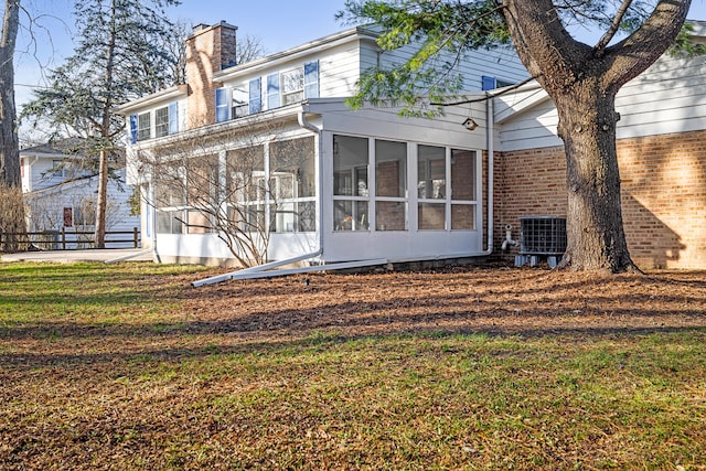 rear view of house with a sunroom, central AC unit, and a yard