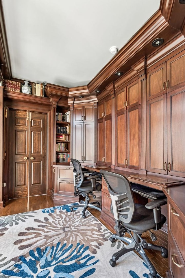 home office featuring built in desk, dark hardwood / wood-style floors, built in features, and ornamental molding