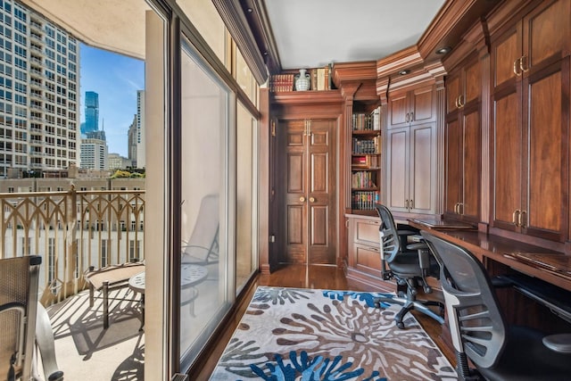 office area featuring dark hardwood / wood-style flooring, built in desk, and ornamental molding