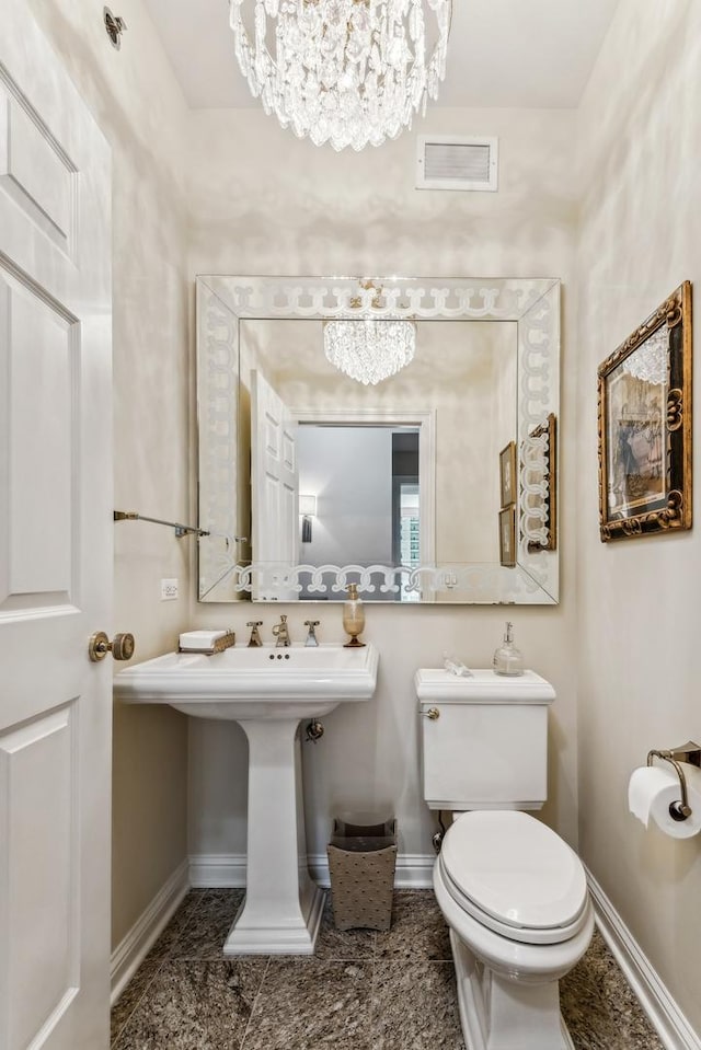 bathroom with toilet and a notable chandelier