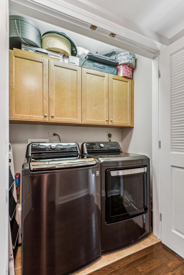 washroom with dark wood-type flooring, cabinets, and independent washer and dryer