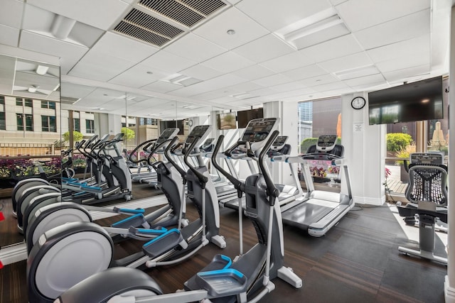 exercise room with floor to ceiling windows, plenty of natural light, and a drop ceiling