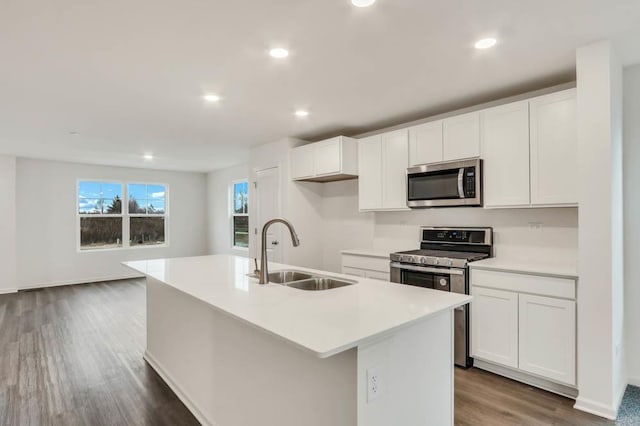 kitchen featuring white cabinetry, sink, dark hardwood / wood-style floors, a center island with sink, and appliances with stainless steel finishes