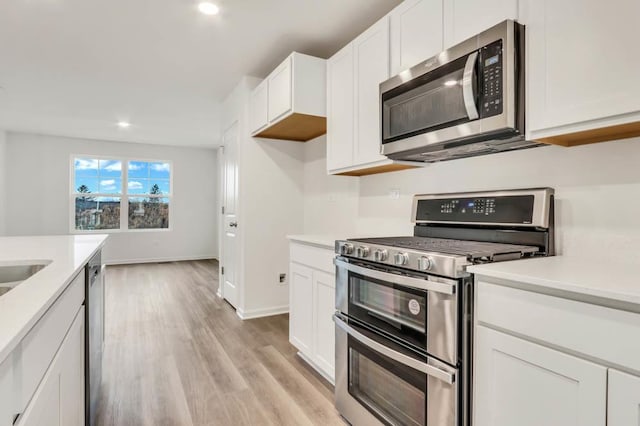 kitchen featuring appliances with stainless steel finishes, light wood-type flooring, and white cabinetry