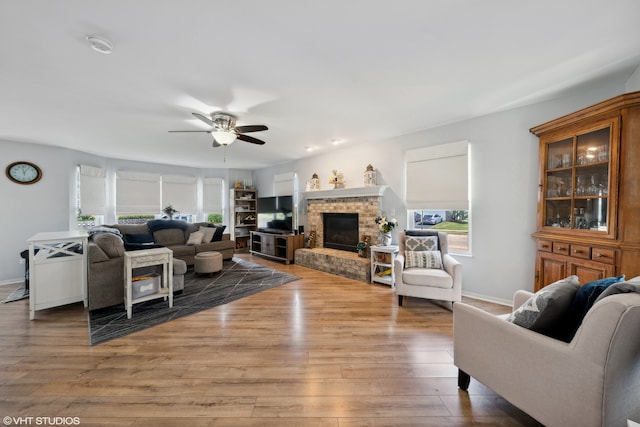 living room featuring ceiling fan, light hardwood / wood-style flooring, and a brick fireplace