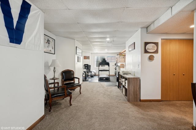 living area featuring light carpet and a paneled ceiling