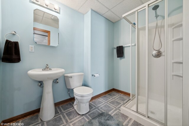 bathroom featuring tile patterned flooring, a paneled ceiling, toilet, and a shower with door