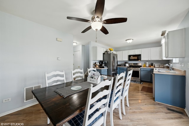 dining space featuring light wood-type flooring, ceiling fan, and sink