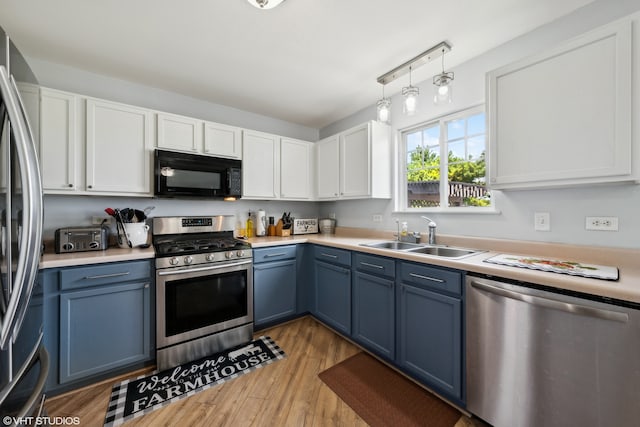 kitchen with appliances with stainless steel finishes, light wood-type flooring, blue cabinets, sink, and white cabinetry