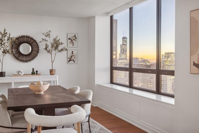 dining area featuring wood finished floors, a wealth of natural light, and a city view