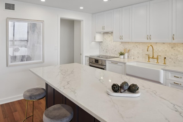 kitchen featuring white cabinets, a sink, oven, and black electric cooktop