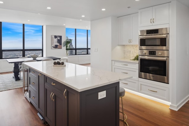 kitchen with double oven, a kitchen island, and white cabinetry