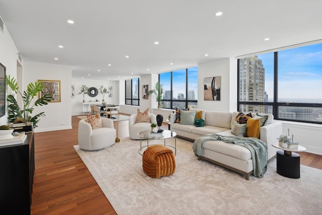 living area with a view of city, baseboards, wood finished floors, and recessed lighting