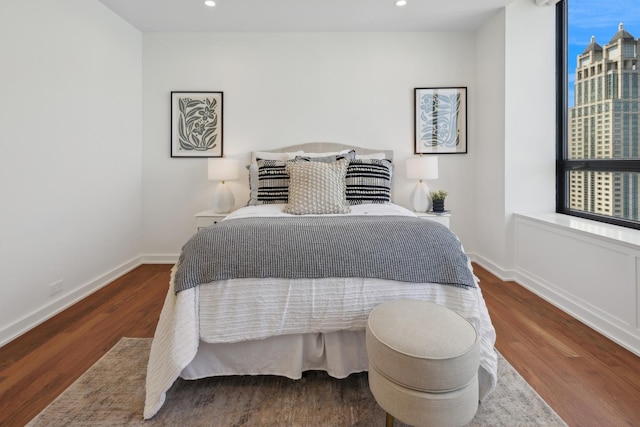 bedroom with multiple windows, baseboards, and wood finished floors