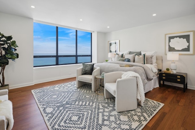 bedroom with recessed lighting, a water view, baseboards, and wood finished floors