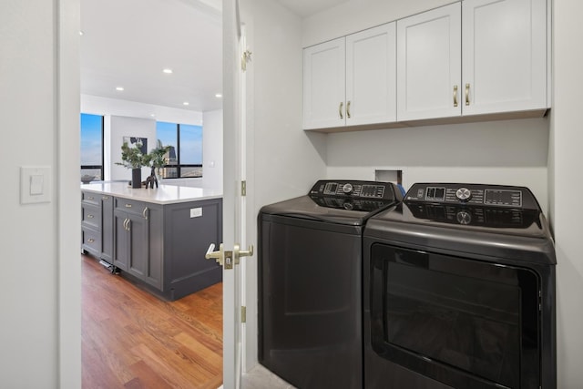 clothes washing area with cabinet space, light wood-style flooring, washer and clothes dryer, and recessed lighting