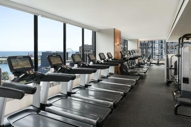 exercise room with a wall of windows and a water view