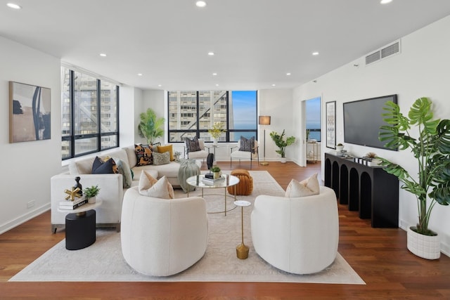 living room with baseboards, visible vents, wood finished floors, and recessed lighting