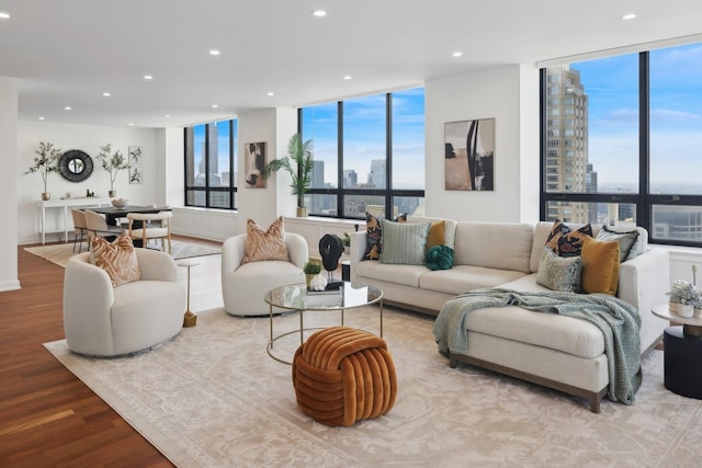 living room featuring a view of city, recessed lighting, wood finished floors, and floor to ceiling windows