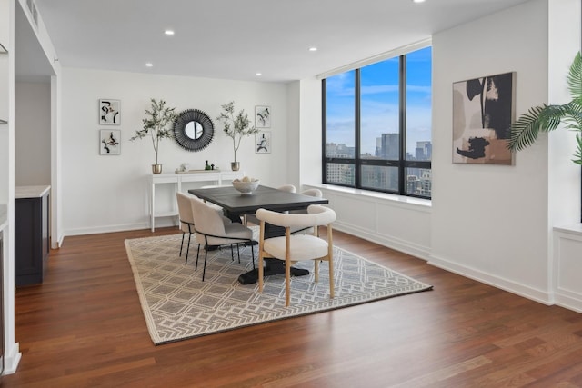 dining space featuring baseboards, recessed lighting, wood finished floors, and a city view