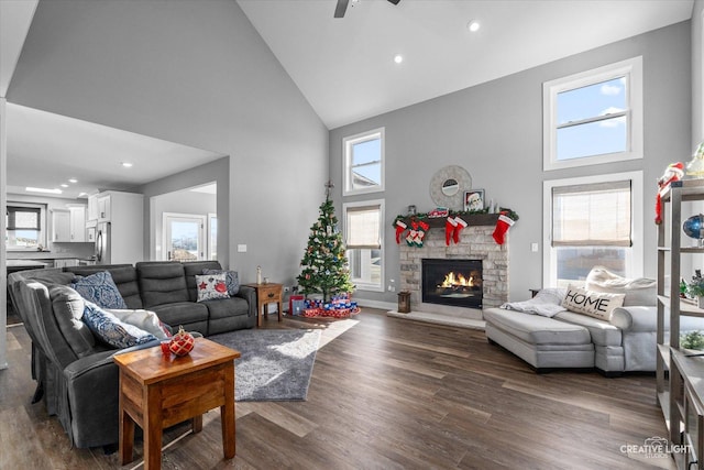 living room featuring ceiling fan, a stone fireplace, dark hardwood / wood-style flooring, and high vaulted ceiling