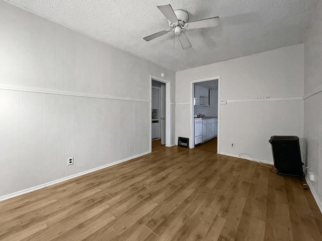 interior space with hardwood / wood-style floors, ceiling fan, a textured ceiling, and connected bathroom