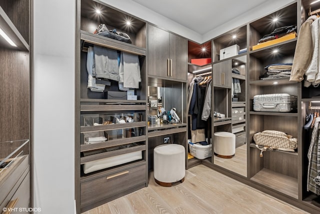 walk in closet with light hardwood / wood-style flooring