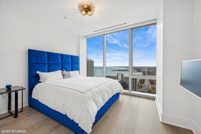 bedroom featuring hardwood / wood-style flooring, floor to ceiling windows, and a water view