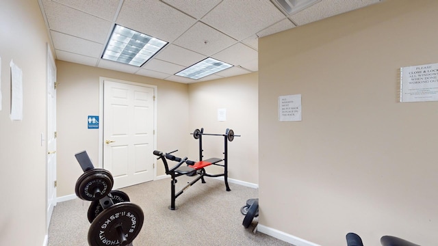 exercise area with carpet floors, a paneled ceiling, and baseboards