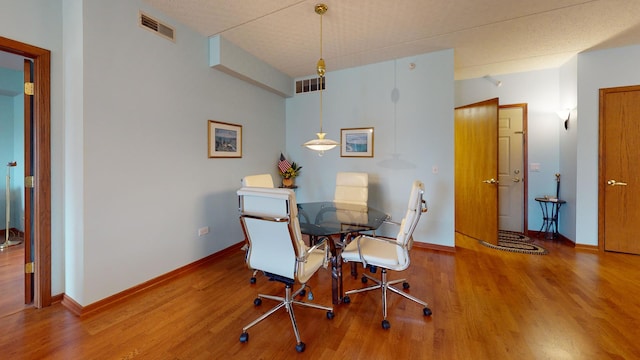 dining space with wood finished floors, visible vents, and baseboards