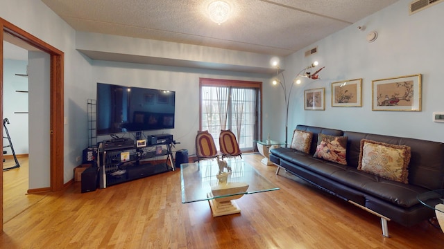 living area featuring a textured ceiling, wood finished floors, and visible vents