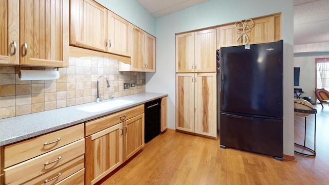 kitchen featuring light countertops, light wood-style flooring, light brown cabinetry, a sink, and black appliances