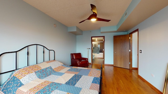 bedroom featuring visible vents, a ceiling fan, a textured ceiling, wood finished floors, and baseboards