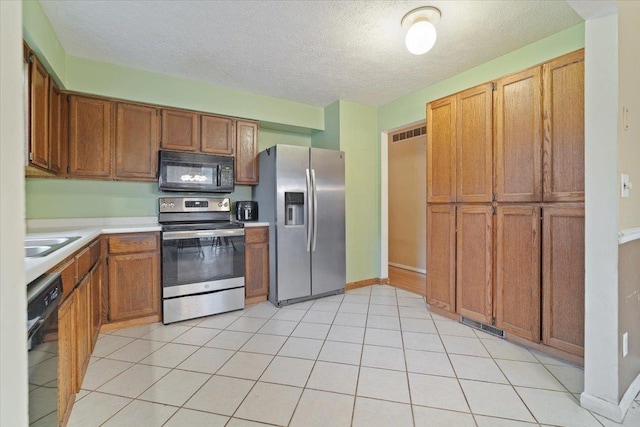 kitchen featuring black appliances, light tile patterned floors, sink, and a textured ceiling