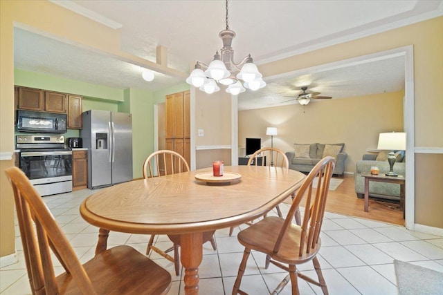 tiled dining room featuring ceiling fan with notable chandelier, ornamental molding, and a textured ceiling