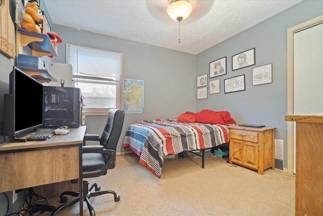 carpeted bedroom featuring ceiling fan and a textured ceiling