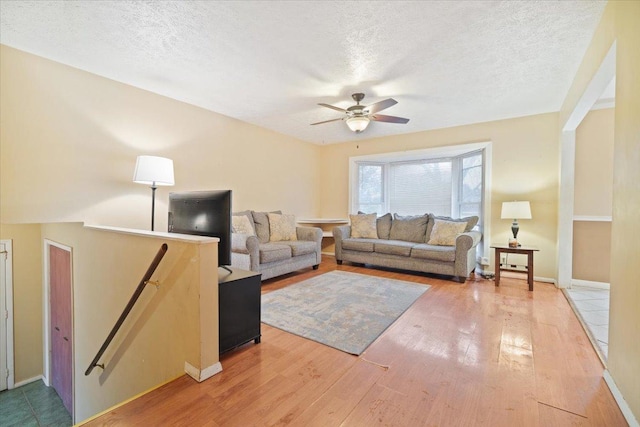 living room featuring hardwood / wood-style floors, a textured ceiling, and ceiling fan