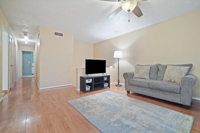 living room with a textured ceiling, hardwood / wood-style flooring, and ceiling fan