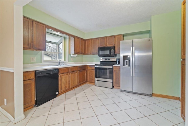 kitchen with black appliances, light tile patterned flooring, sink, and a textured ceiling